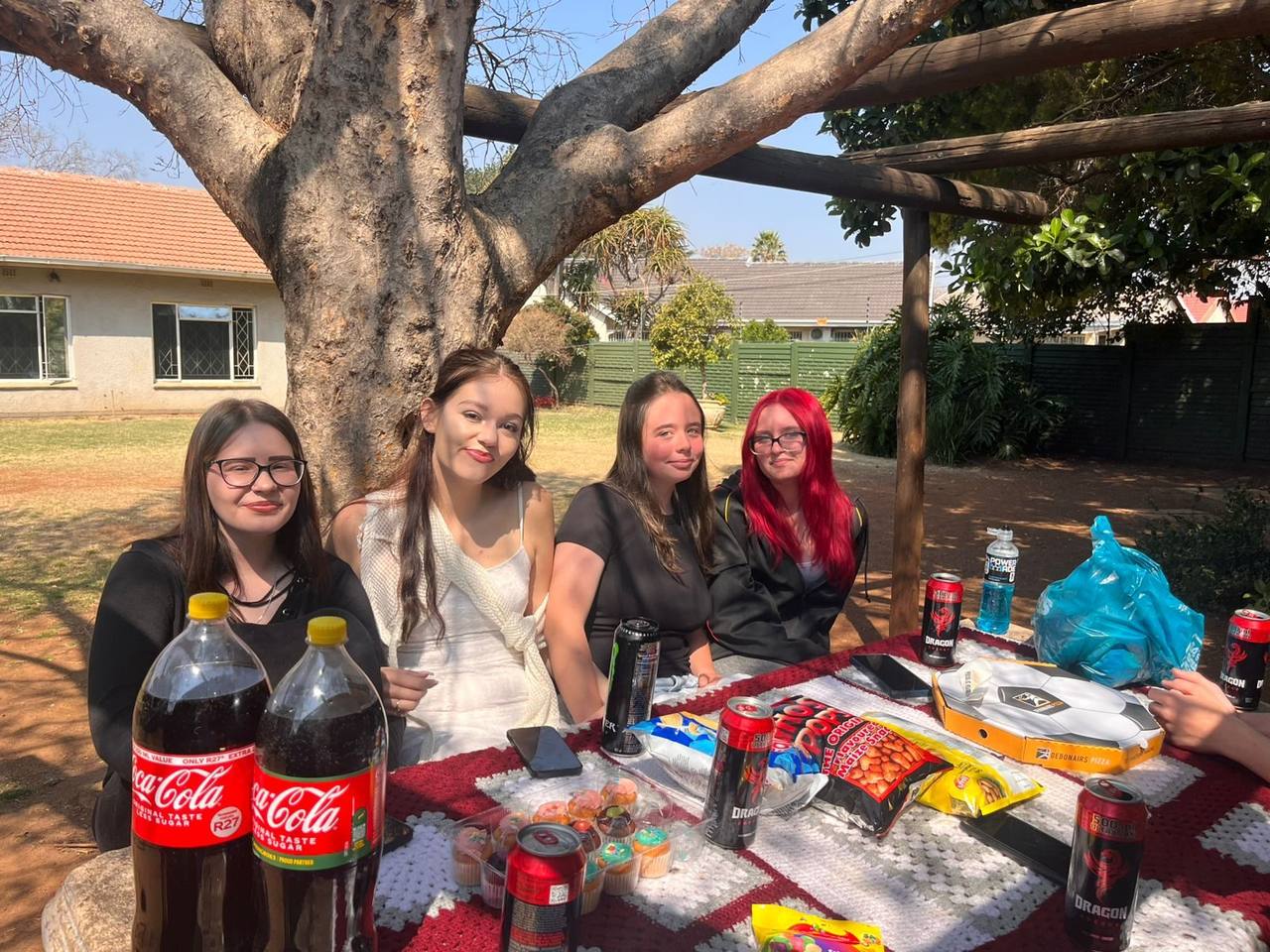Learners at the picnic table under the tree at St. Ronald's Homeschool Tutor Centre Spring Picnic